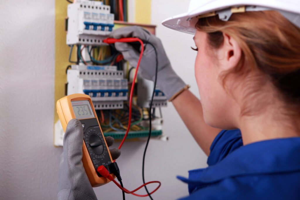 Female electrician taking reading from fuse box